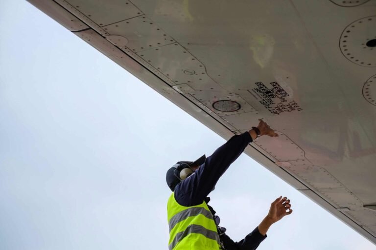 An employee inspects underside of an aeroplane wing