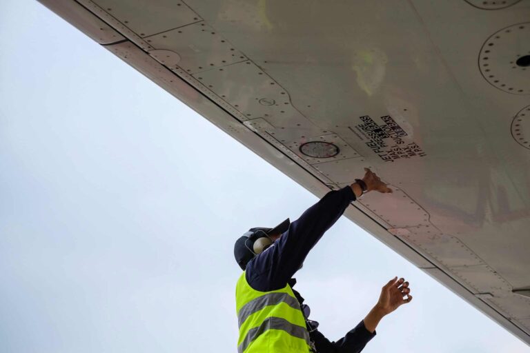 An employee inspects underside of an aeroplane wing