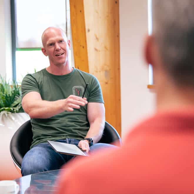 A man in. a green shirt talks to another person, opposite him