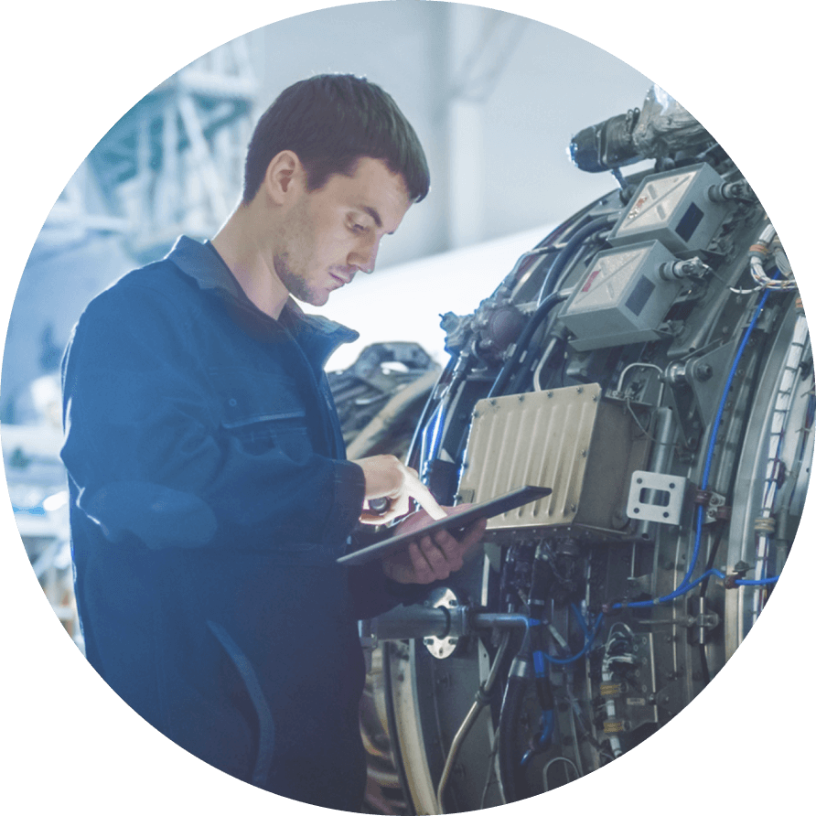 A man works on a tablet, during maintenance on a jet engine