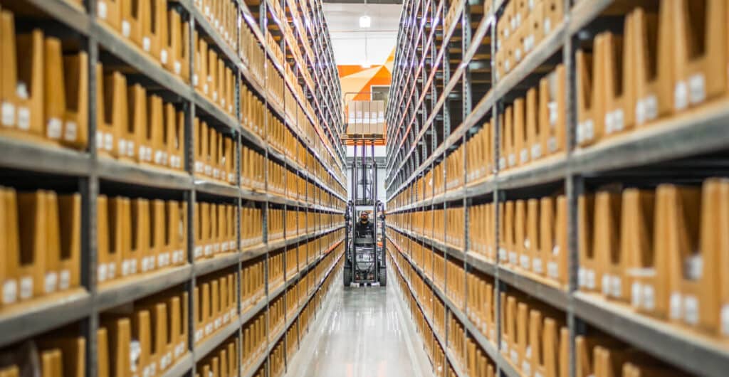 A man drives a forklift through a warehouse