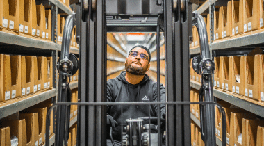 A man drives a forklift through a warehouse