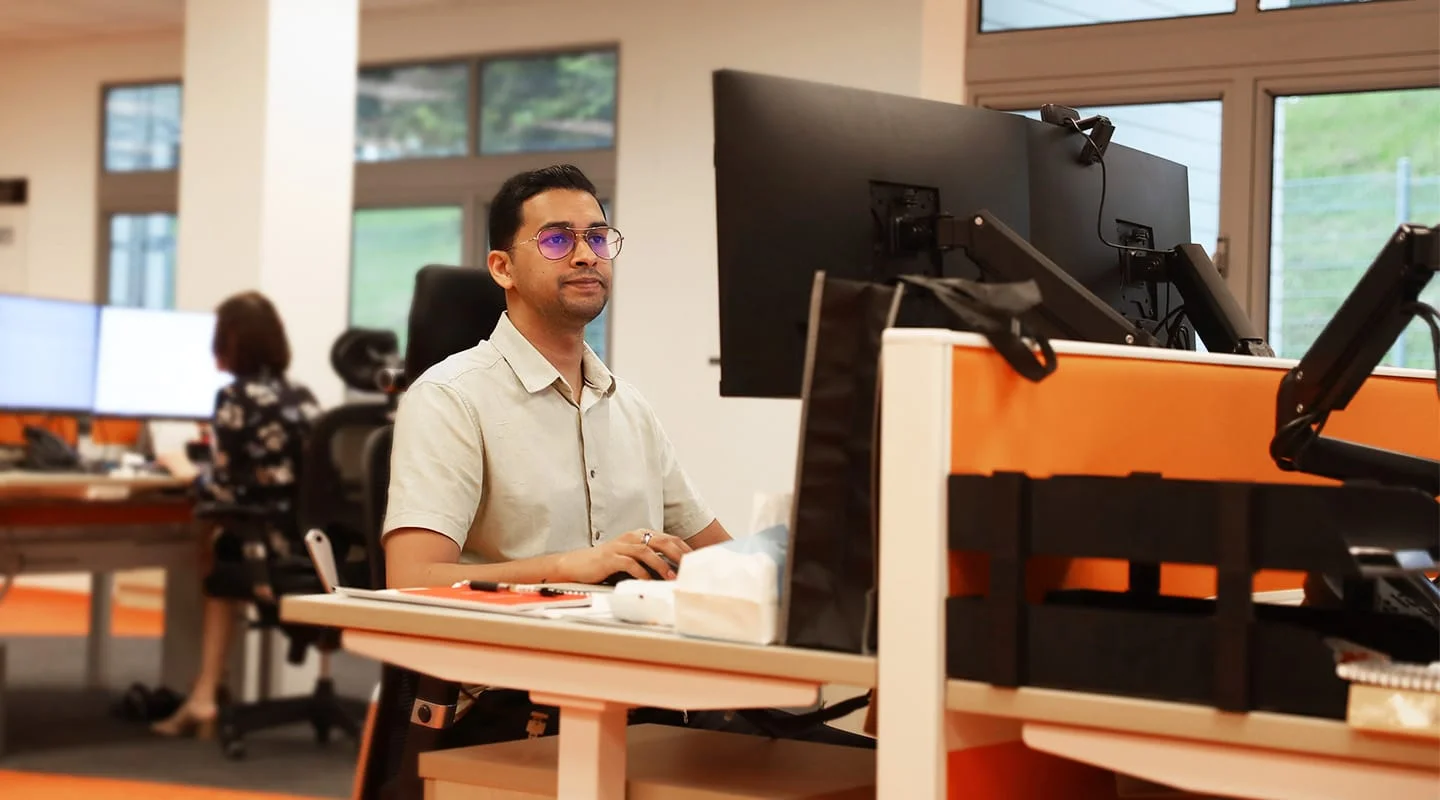 A man in glasses and short sleeve shirt, sits at a computer
