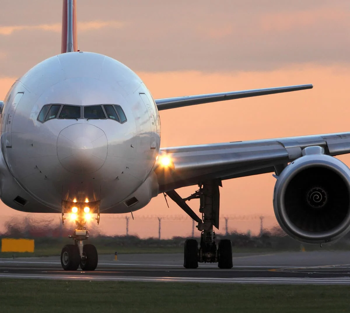 A Boeing 777 taxiing on the runway after landing at sunset
