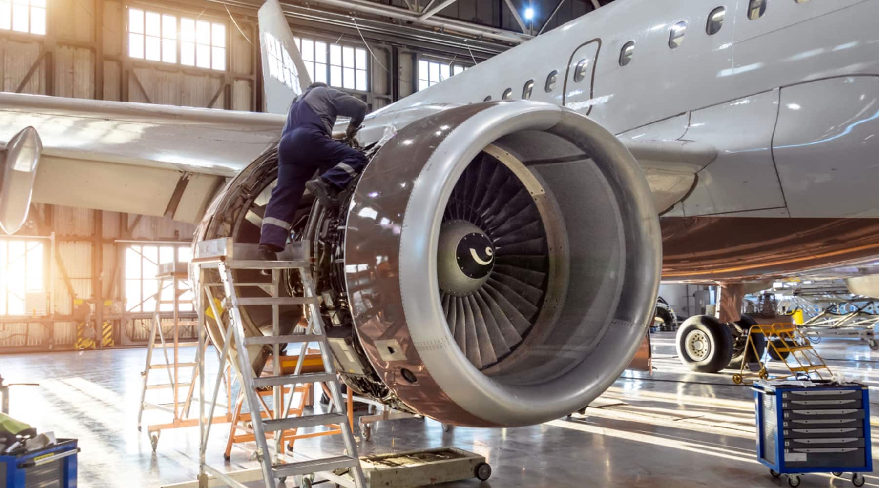 A man performs maintenance on a jet engine