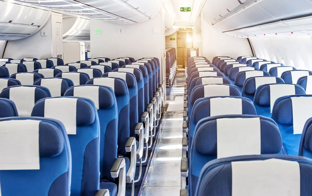 Well lit shot of the inside of an aeroplane. Showing three banks of three row, blue seats