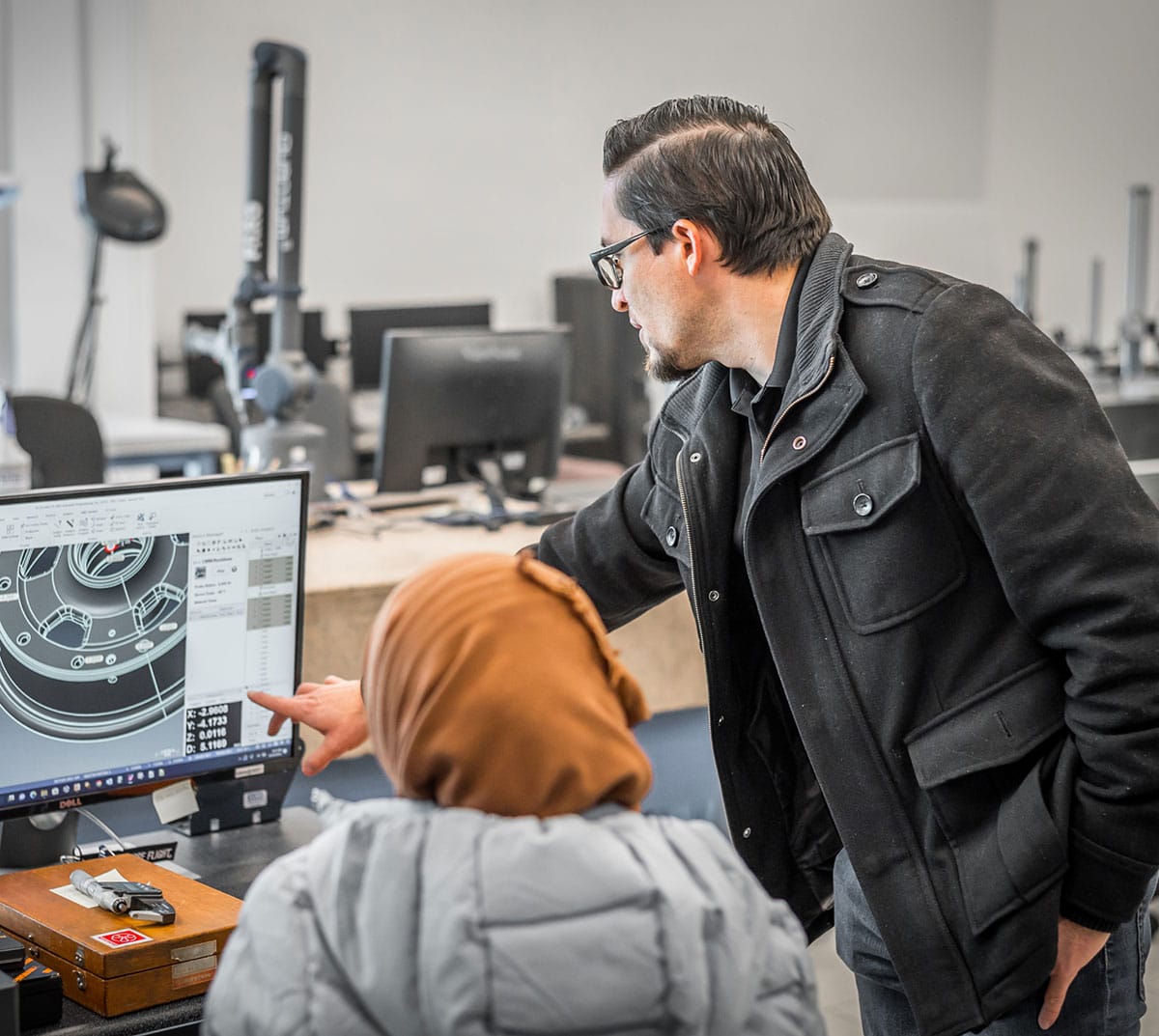 Employees working at a computer screen, looking at CAD software