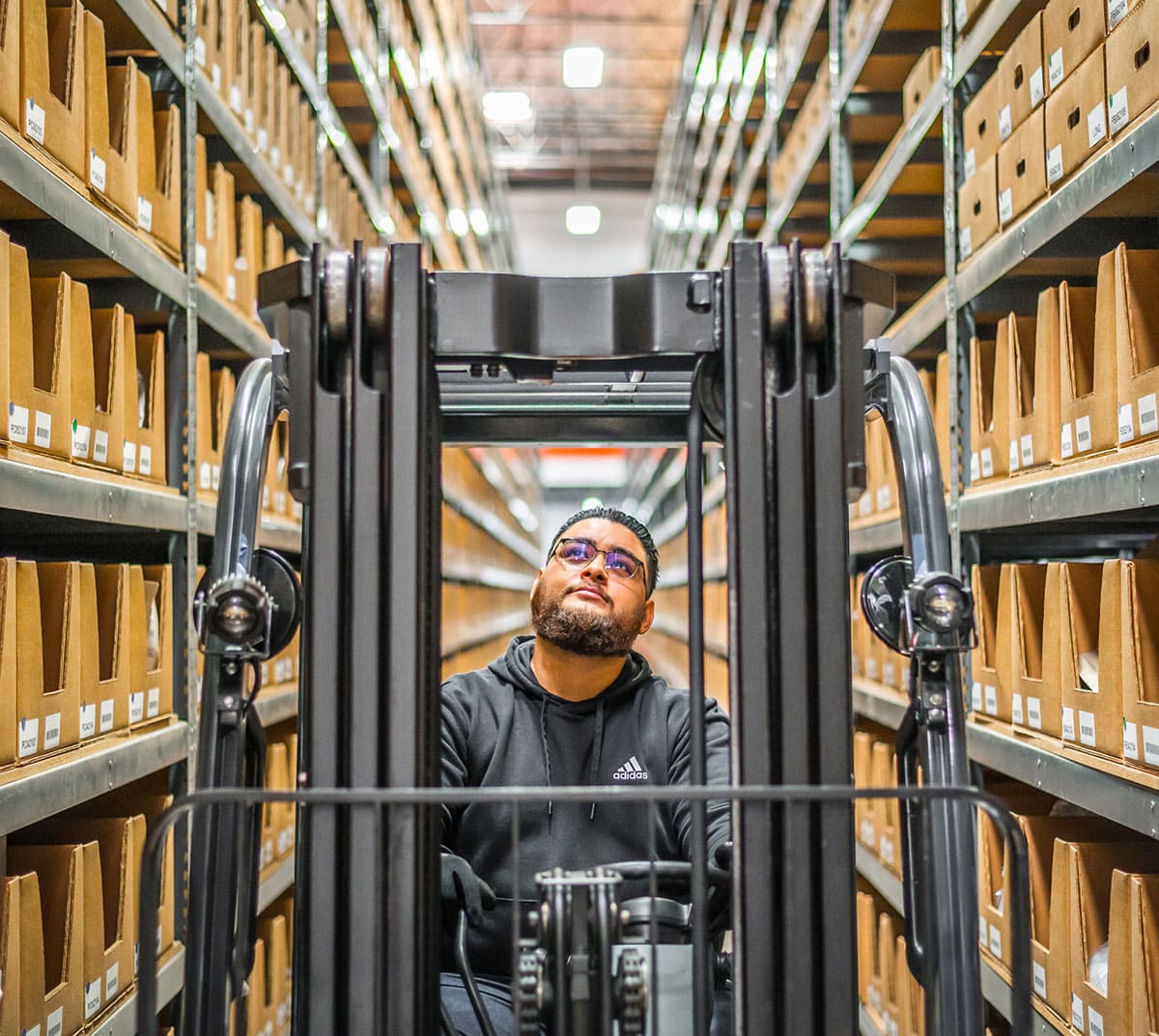 An employee drives a forklift through a warehouse