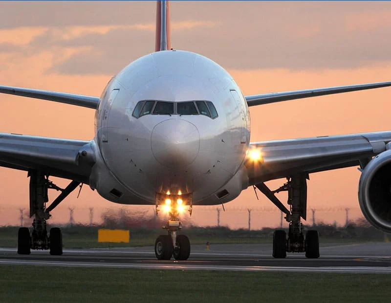 White Boeing 777 taxiing on the runway after landing at sunset