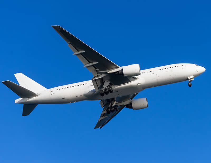 Undershot of a white Boeing 777, with its landing gear down