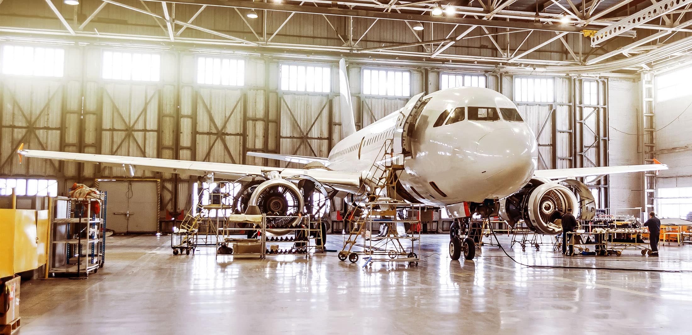 Large, white, twin engine, jet plane being repaired in a hanger