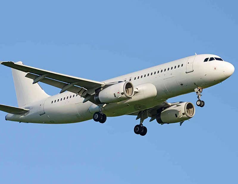 White, twin engine jet aeroplane in the air, with its landing gear down