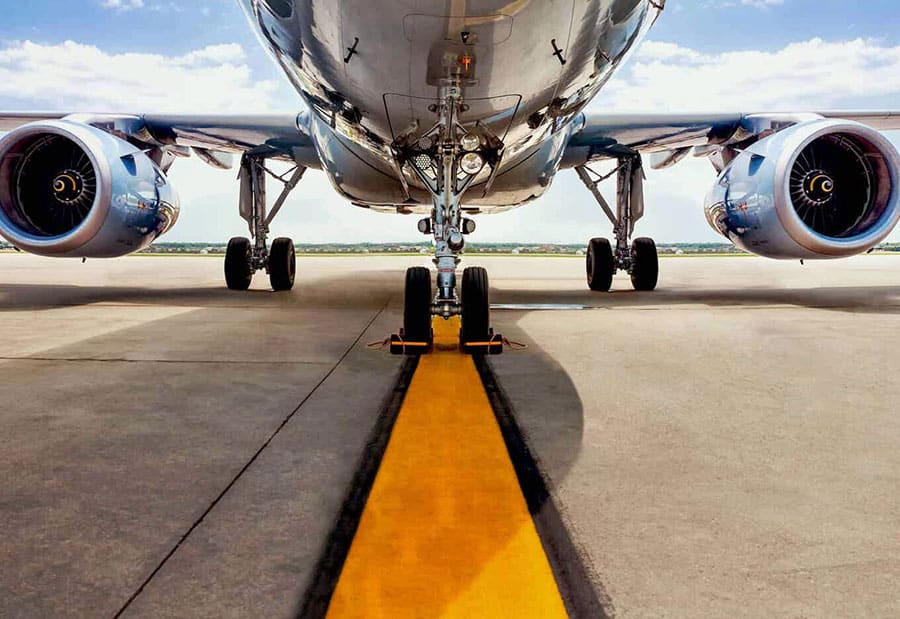 Front shot of a twin jet engine aircraft. Landing gear is down and lined up on the runway, with chocks